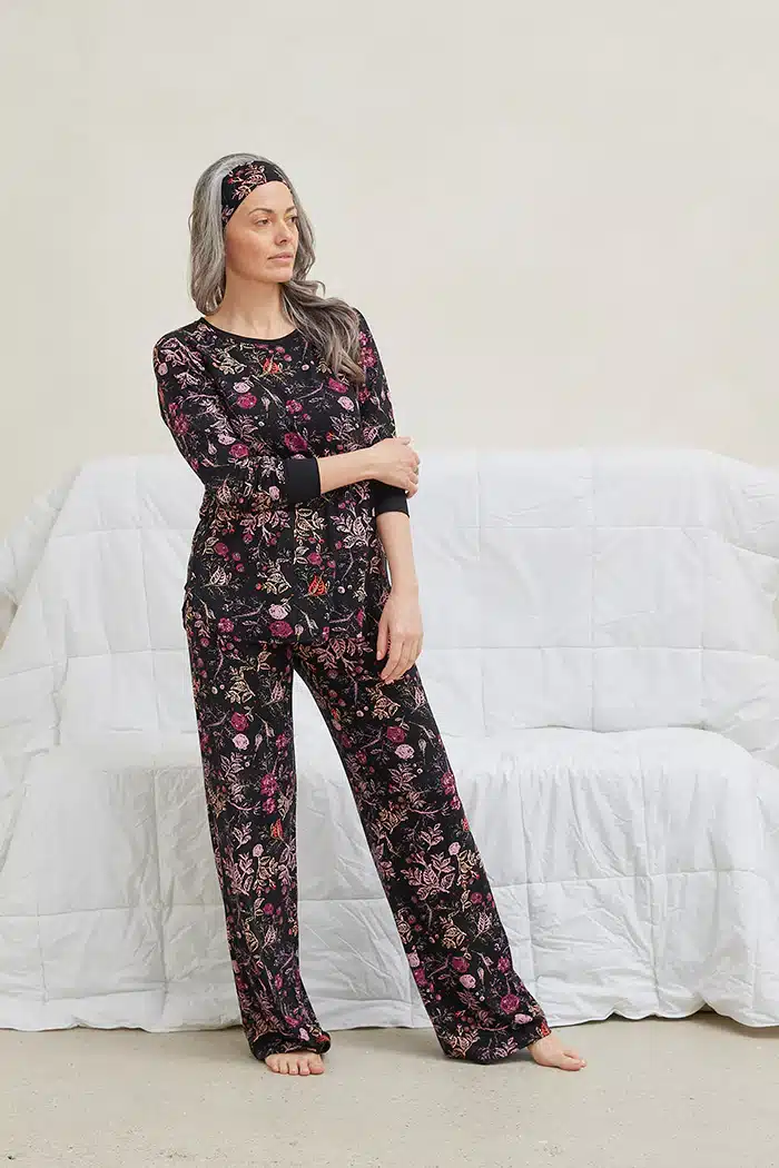 Why Bamboo Pajamas are the Best Choice for Sensitive Skin 14 Person with long hair wearing floral pajamas and a matching headband stands in front of a white sofa with a quilt.