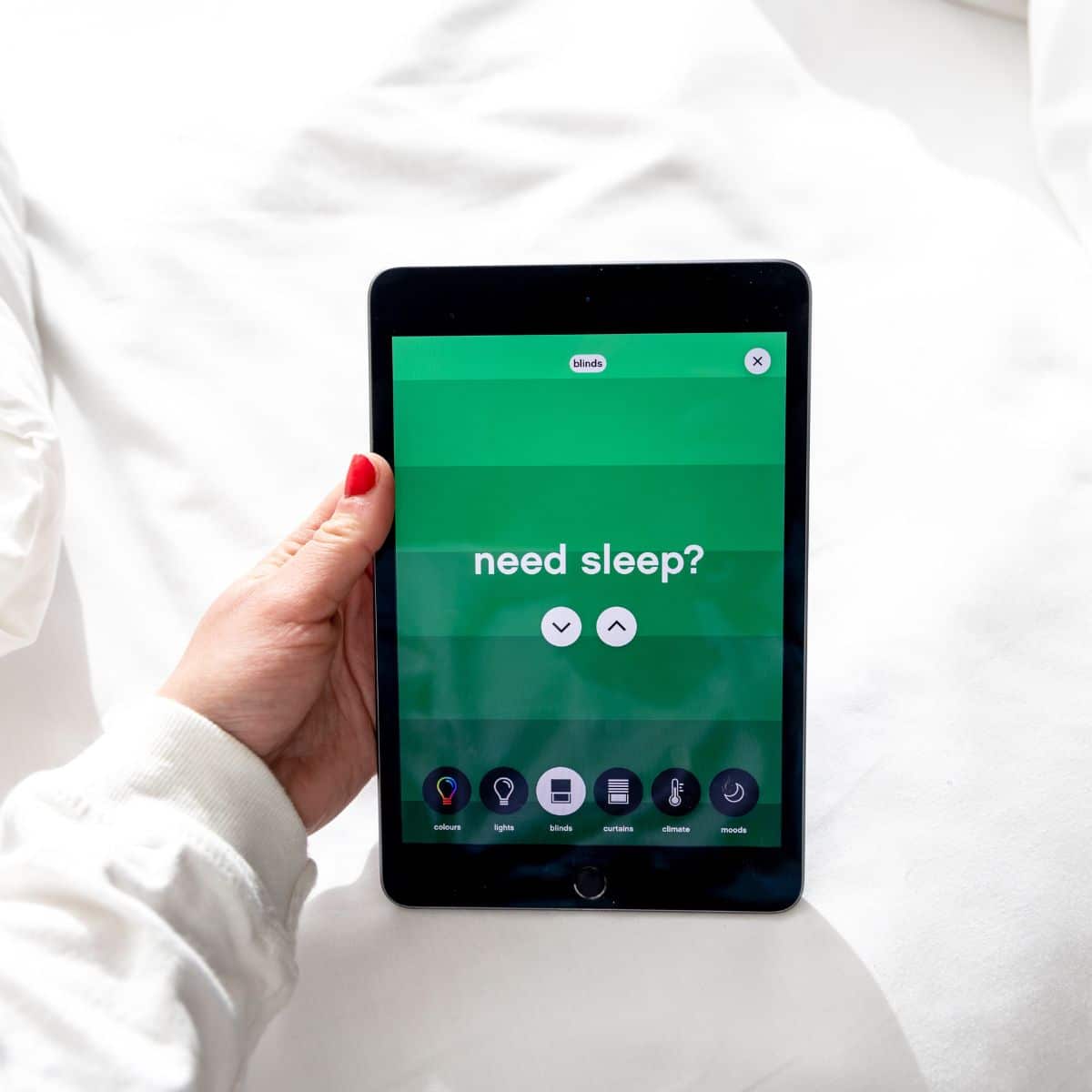 Hand holding a tablet with a screen displaying the text "need sleep?" on a green background.