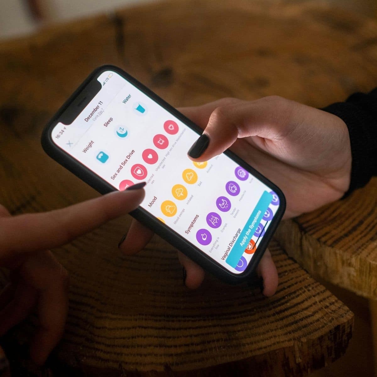 A person holds a smartphone displaying a health tracking app while another person points at the screen.