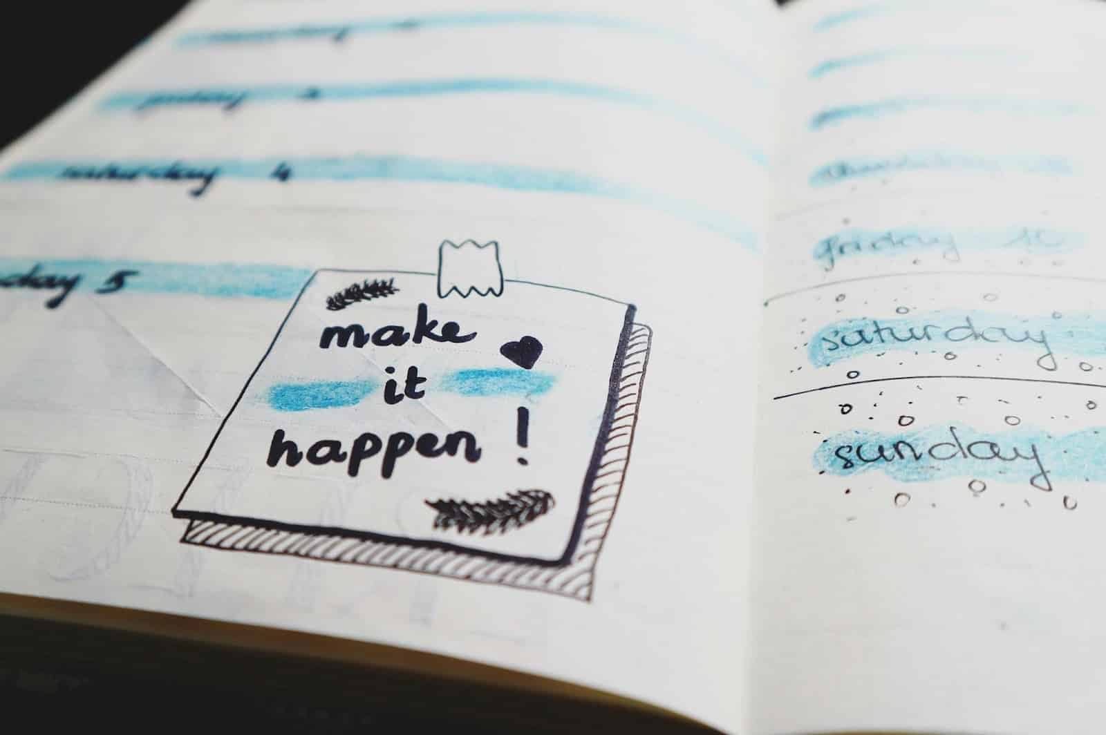Open notebook with handwritten weekly planner, blue highlights, and a note reading "make it happen!" decorated with doodles and a heart.