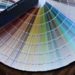 A fan of paint colour swatches arranged in a semi-circle, displaying a range of shades from neutral tones to brighter colours. The swatches are labelled with names and codes.