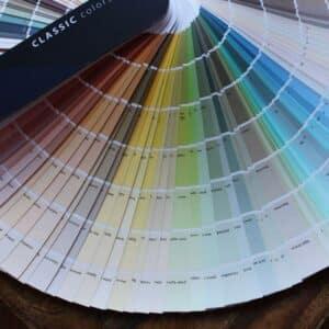 A fan of paint colour swatches arranged in a semi-circle, displaying a range of shades from neutral tones to brighter colours. The swatches are labelled with names and codes.