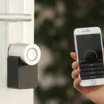 A person uses a smartphone app to control a smart lock fitted to a door.